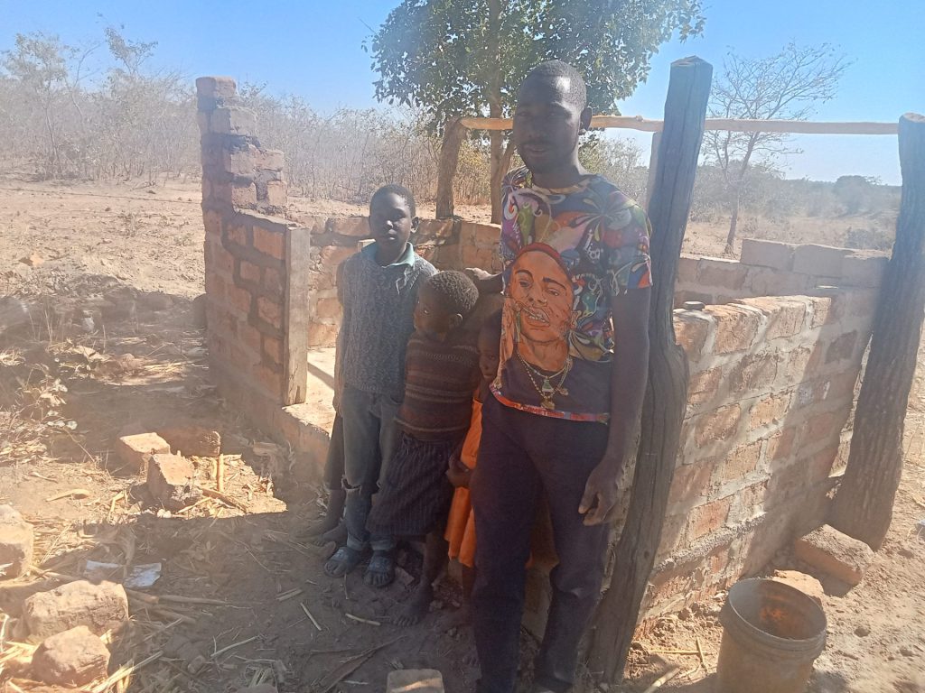 One of the beneficiary stands outside his piggery unit that is still under construction