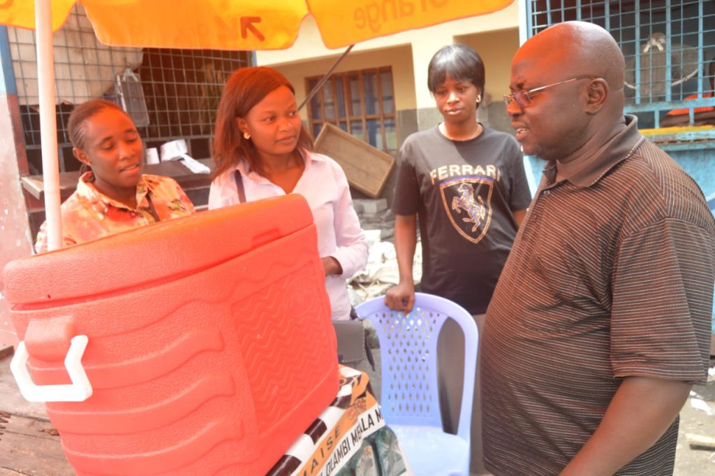 Fr. Kubanabantu Jean-Charles, Director of Centre Maisha, during his visit to Anita Nato and Deborah Angeli at their business, as AJAN continues to accompany and support them in their entrepreneurial journey.